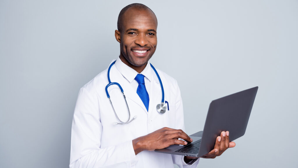 Médico afro-americano segurando um computador e sorrindo