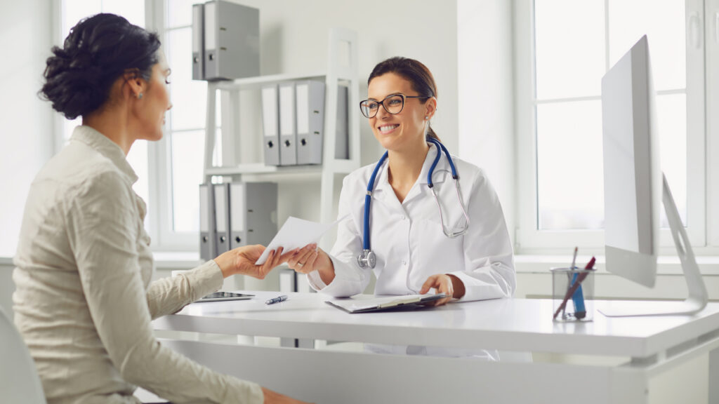 Paciente pegando receita médica com uma médica mulher